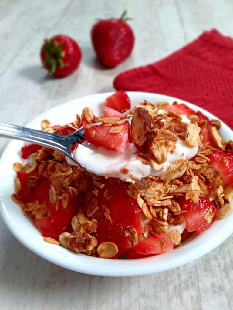 a dish with granola cereal, yogurt, and berries.