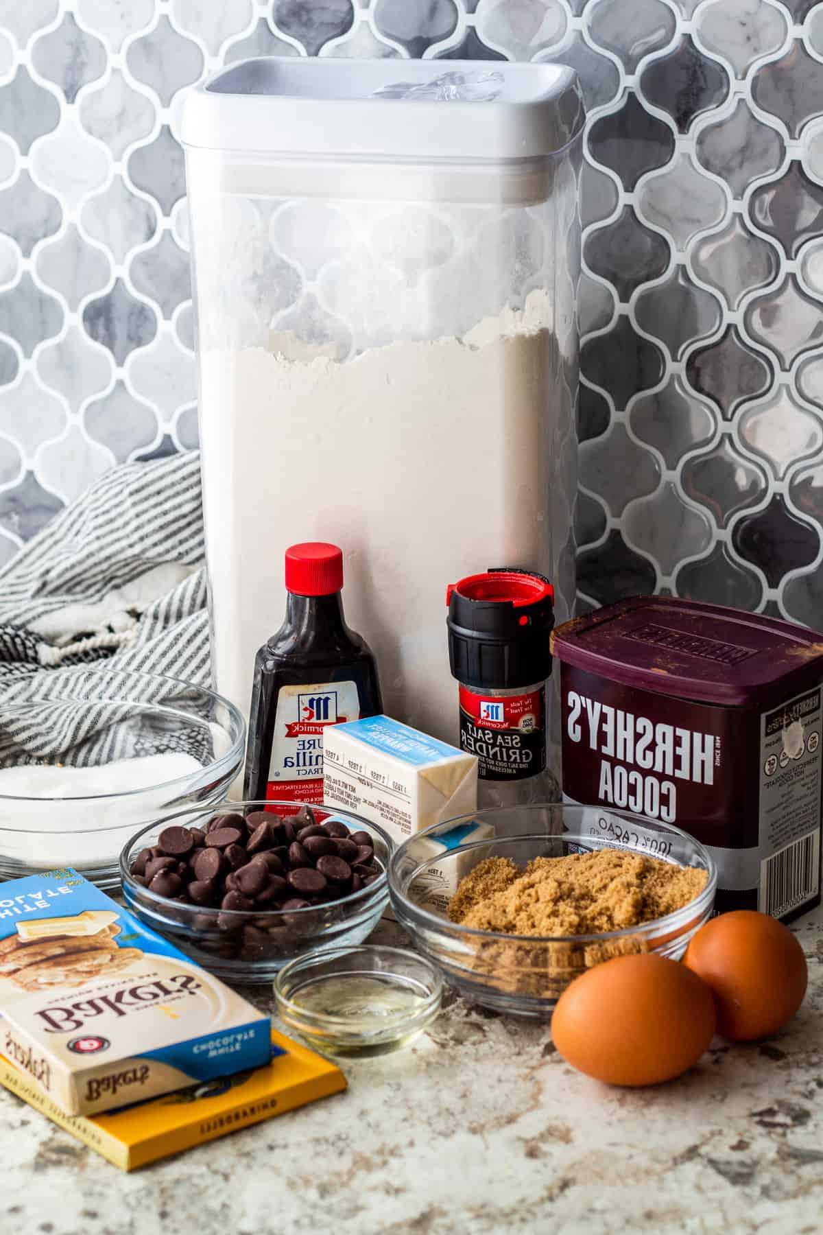 Brownie ingredients laid out on white counter in containers and small bowls.