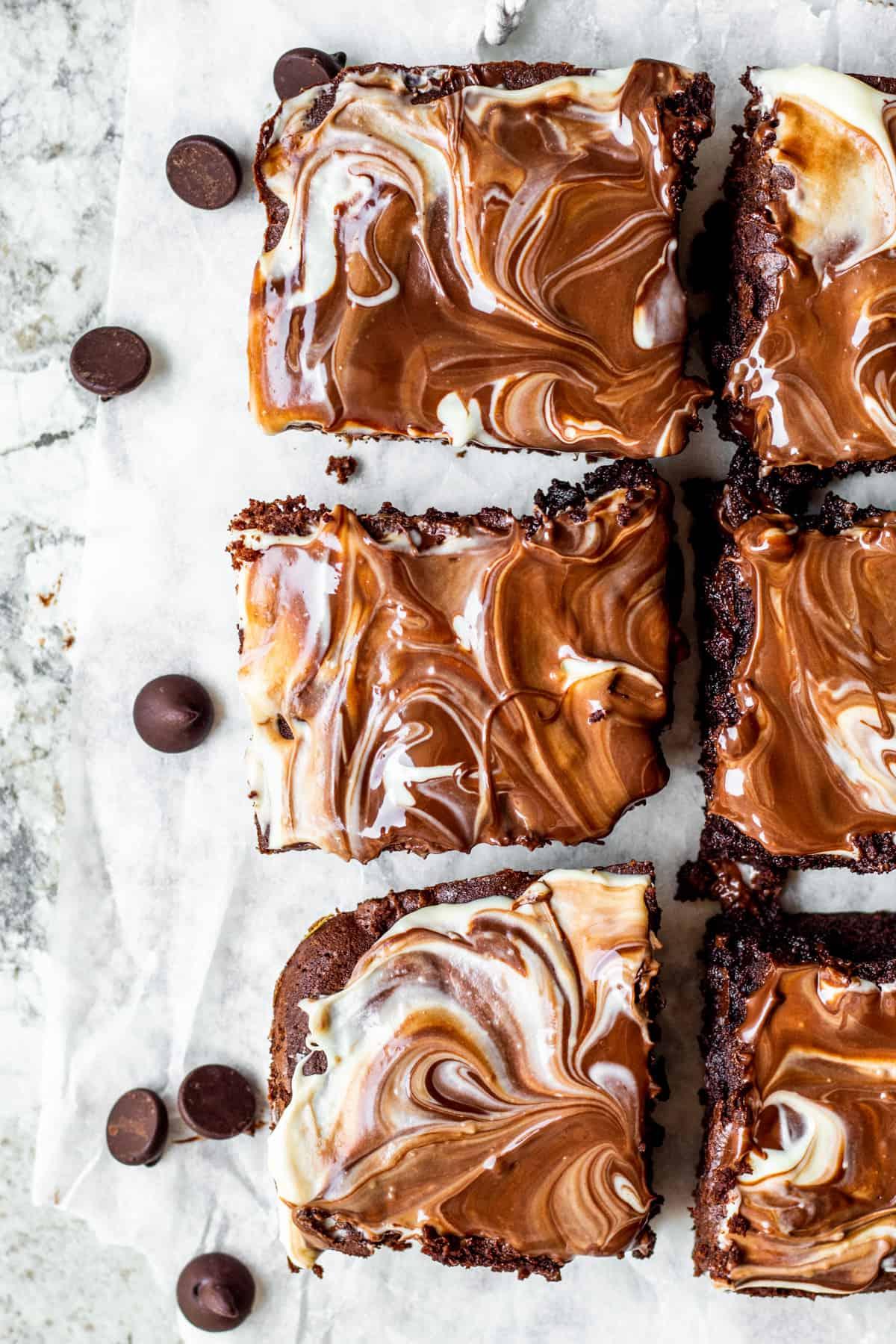 Overhead shot of brownies sliced on white parchment paper.