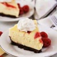Slices of Instant Pot White Chocolate Raspberry Cheesecake topped with whipped cream.