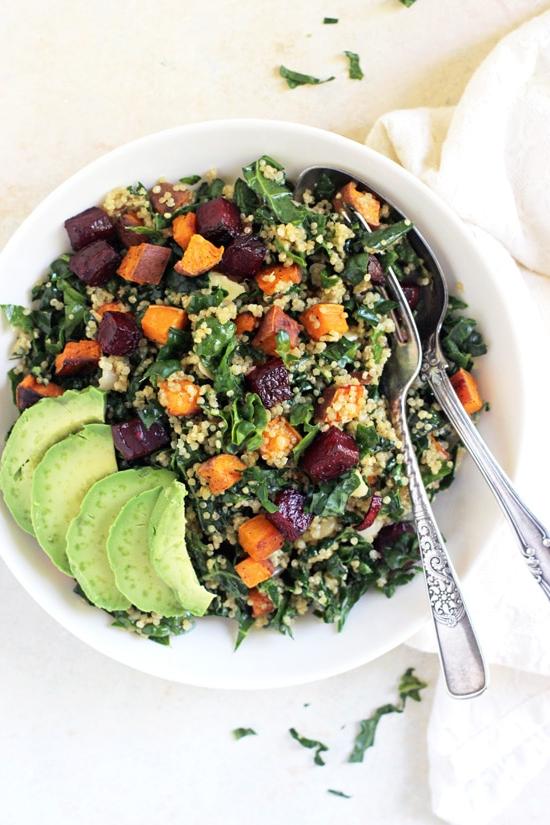 An overhead view of Kale and Quinoa Salad in a bowl with a fork and spoon and a napkin to the side.