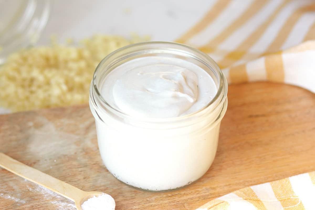 a jar of homemade diaper rash cream with dried lavender flowers and a spoonful of zinc oxide next to it on a wooden cutting board