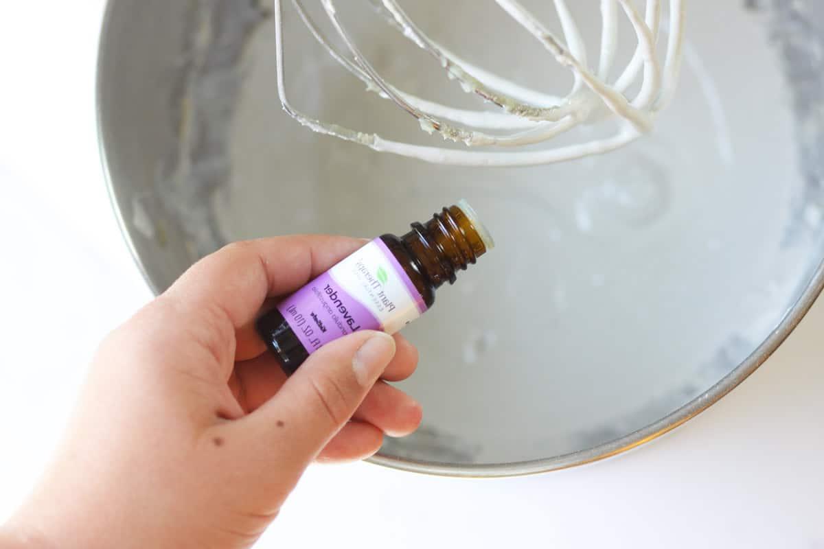 lavender essential oil being added to a kitchenaid mixer of homemade diaper rash cream